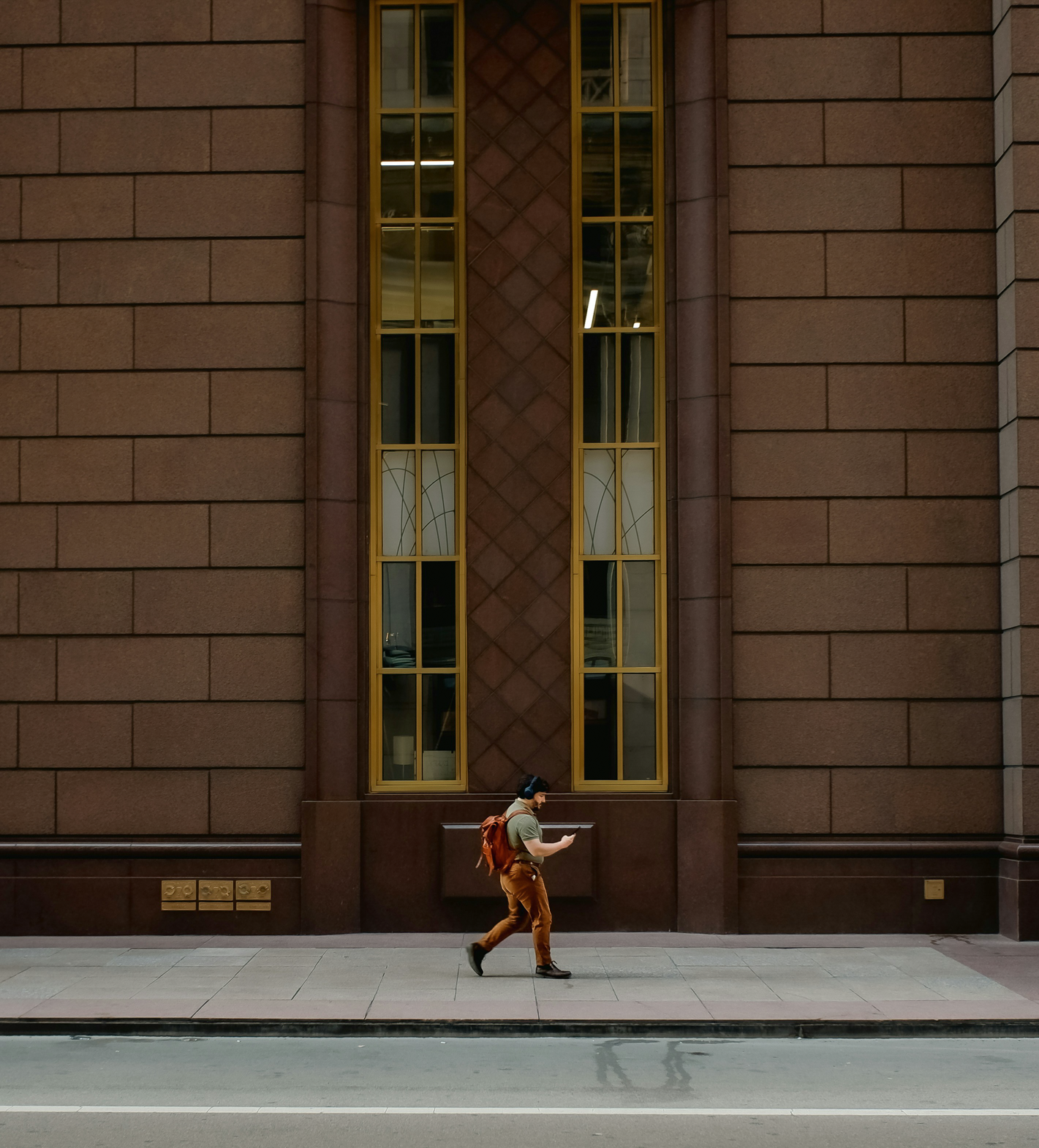 Pedestrian walking along a Chicago sidewalk in front of a mid-century brick building—capturing the everyday movement, vertical lines, and human scale that define the urban fabric and inform real estate decisions.