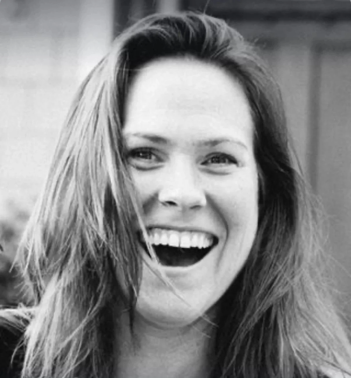Black and white photo of a woman with long hair, smiling with her mouth open.