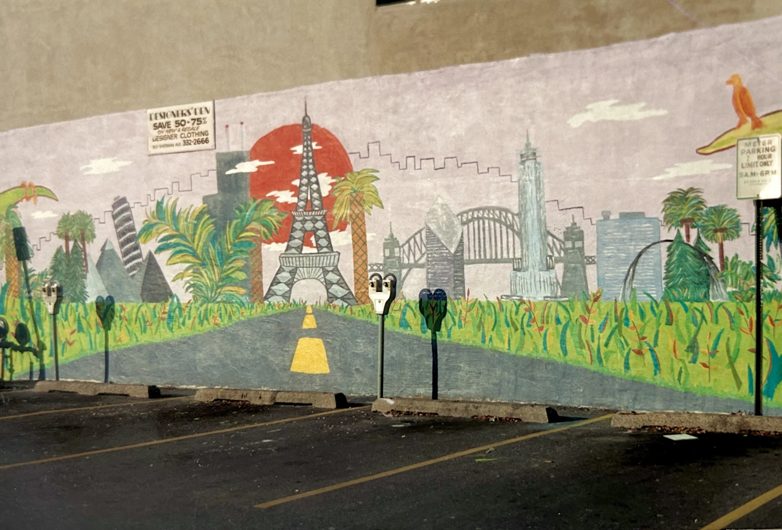 A brightly colored mural features images from around the world including the Eiffel Tower, Leaning Tower of Pisa, and the Golden Gate Bridge next to buildings from the Chicago skyline. The buildings are surrounded by grass and palm trees.