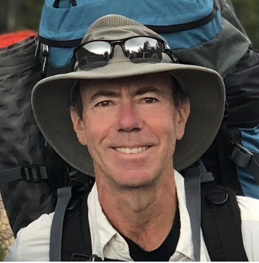 man outdoors wearing a hat with a backpack
