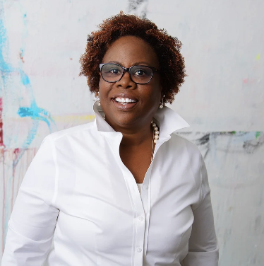 african american woman with wavy mid length hair wearing a white blouse smiling