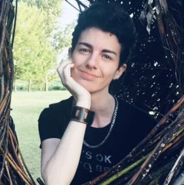 man with short dark hair posing outside