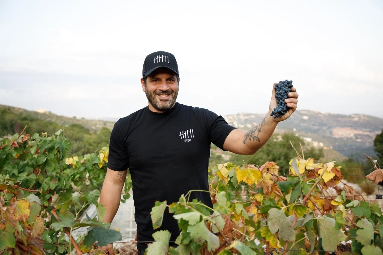 maher harb stands in the midst of sept winery vineyards in lebanon holding a cluster of grapes