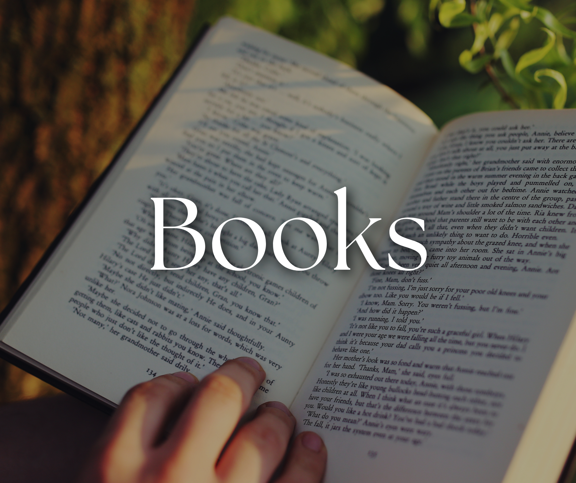 Open book with text in a hand, the word 'Books' written in large font overlayed on the image.
