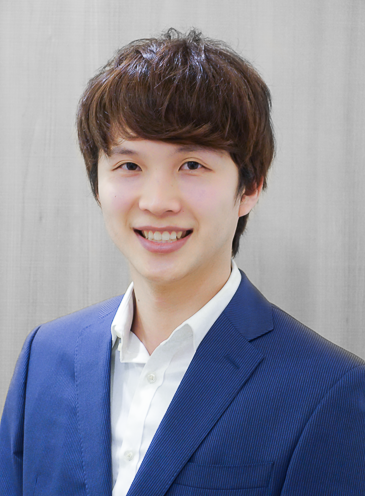 Young man with brown hair in a blue suit smiling at the camera