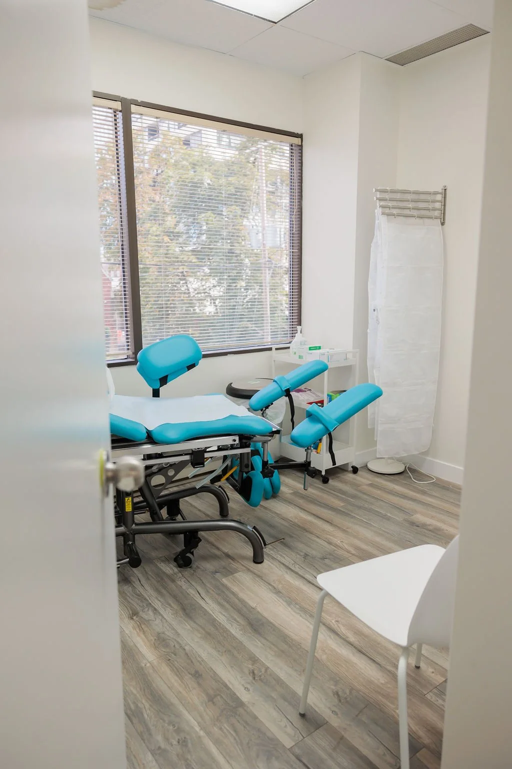 Private pelvic floor physiotherapy exam room with an adjustable treatment table and medical supplies at Toronto Pessary Clinic.