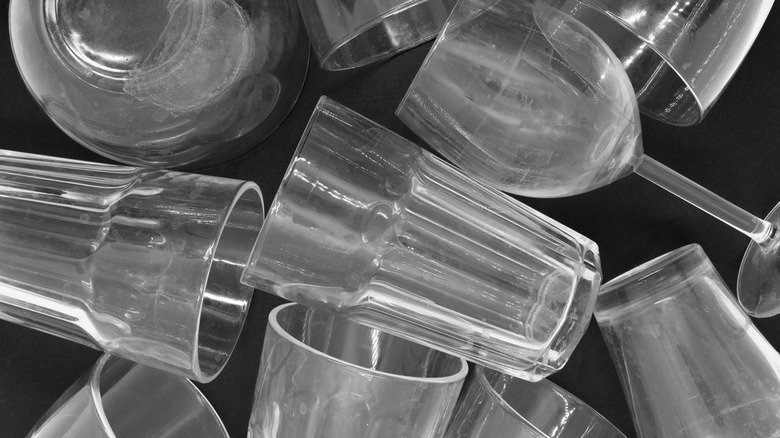 Multiple stained transparent glass drinking cups scattered on a black surface.