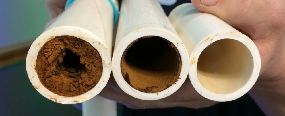 Three white cylindrical tubes held by a hand, with iron inside each one, ranging from dark brown to light beige.