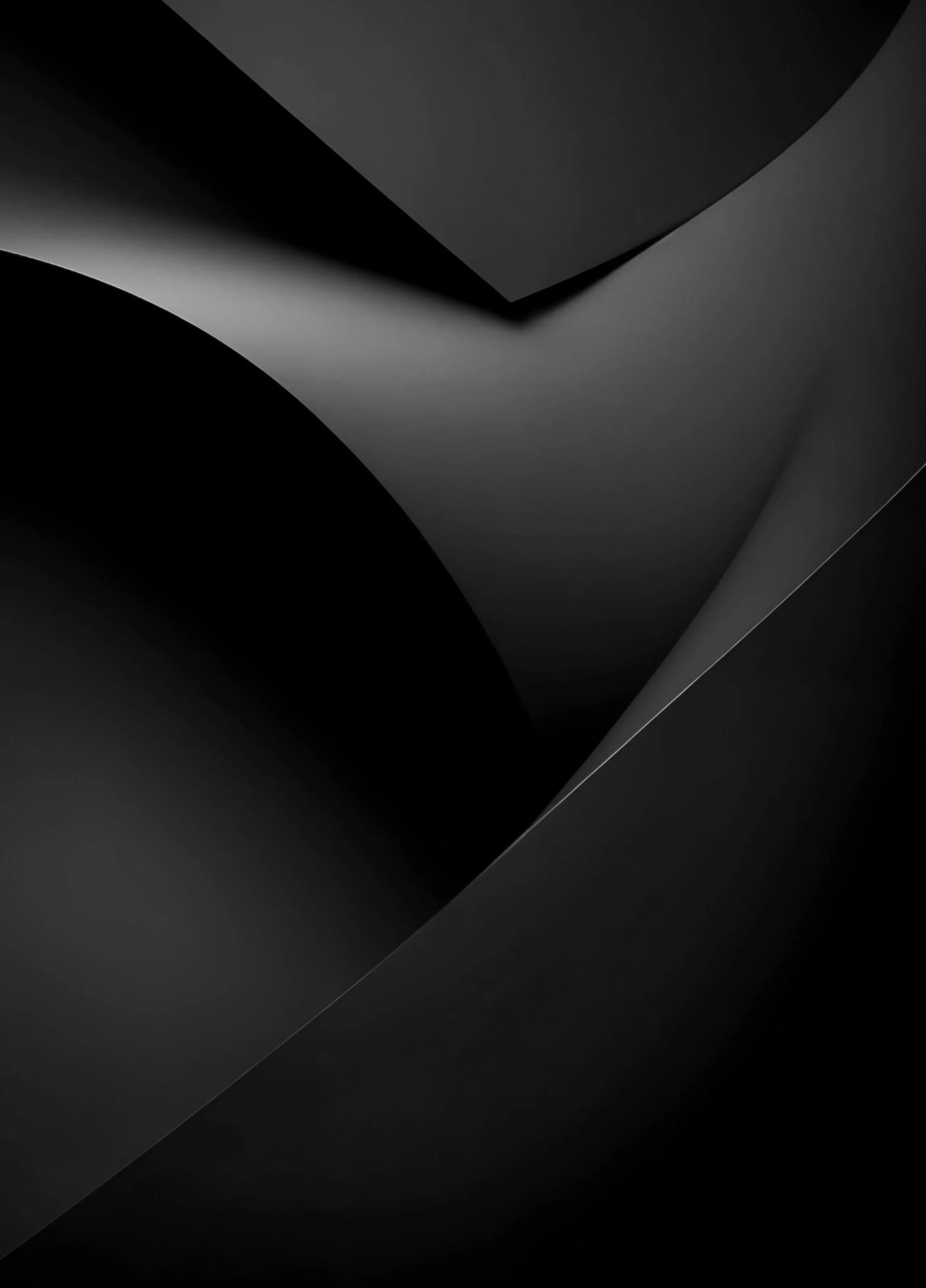 Macro detail of folded charcoal paper stock, light catching the curved edges — Studio Rationale, brand and creative consultancy in Sydney.