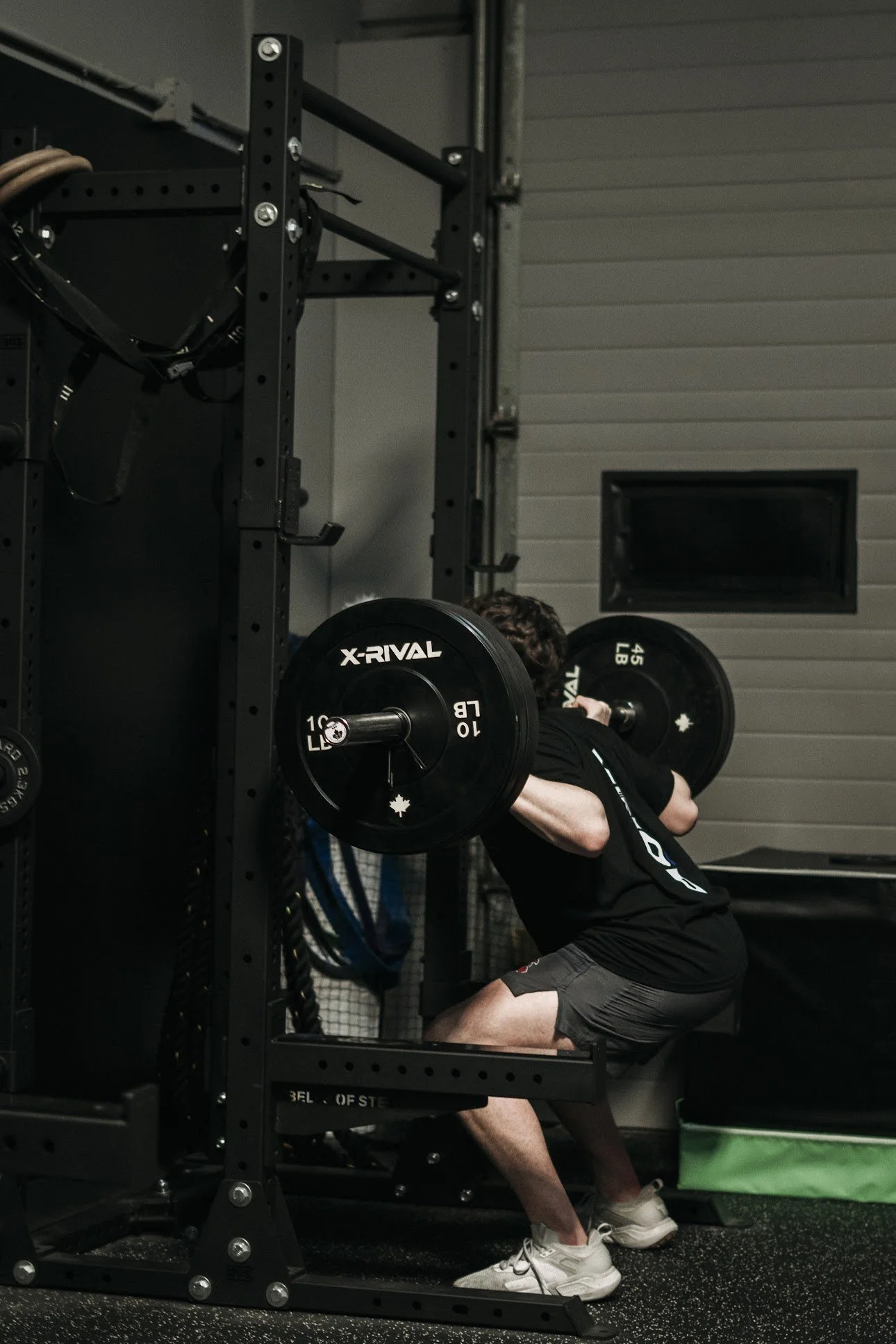 A person performing a squat exercise with a barbell loaded with weight plates in a gym.