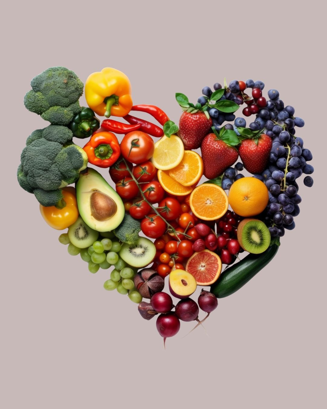 A heart-shaped arrangement of various fresh fruits and vegetables, including broccoli, yellow and red bell peppers, chili peppers, tomatoes, avocado, kiwi, grapes, oranges, strawberries, lemons, cucumbers, and radishes.