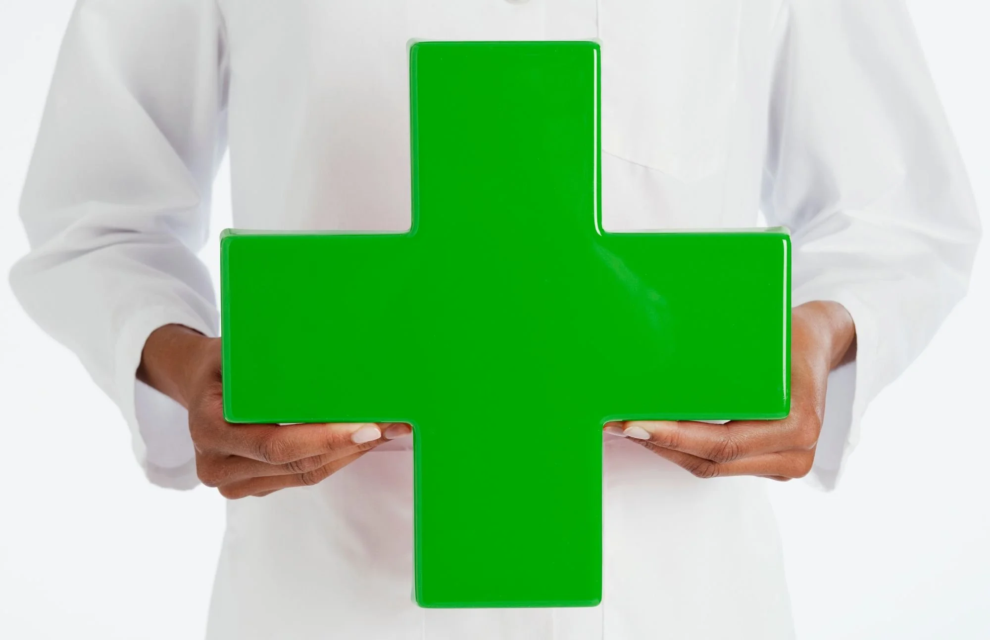 Person in white shirt holding a large green cross symbol