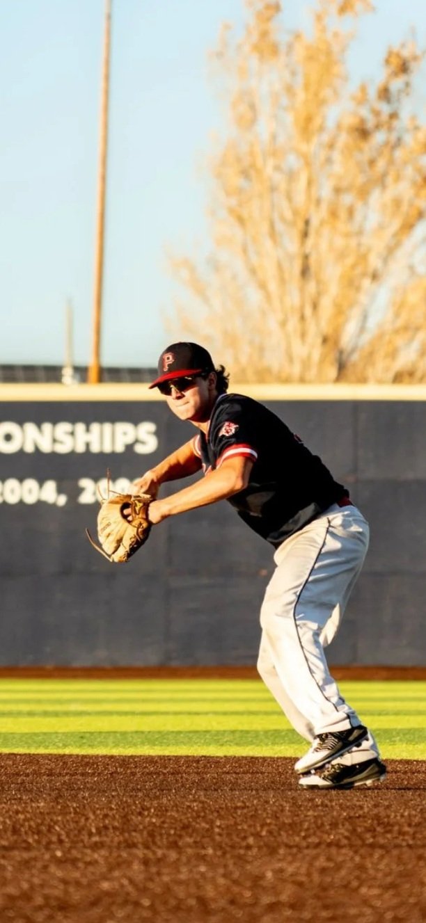 A baseball player in uniform on the field, preparing to catch a ball with his glove during a game.
