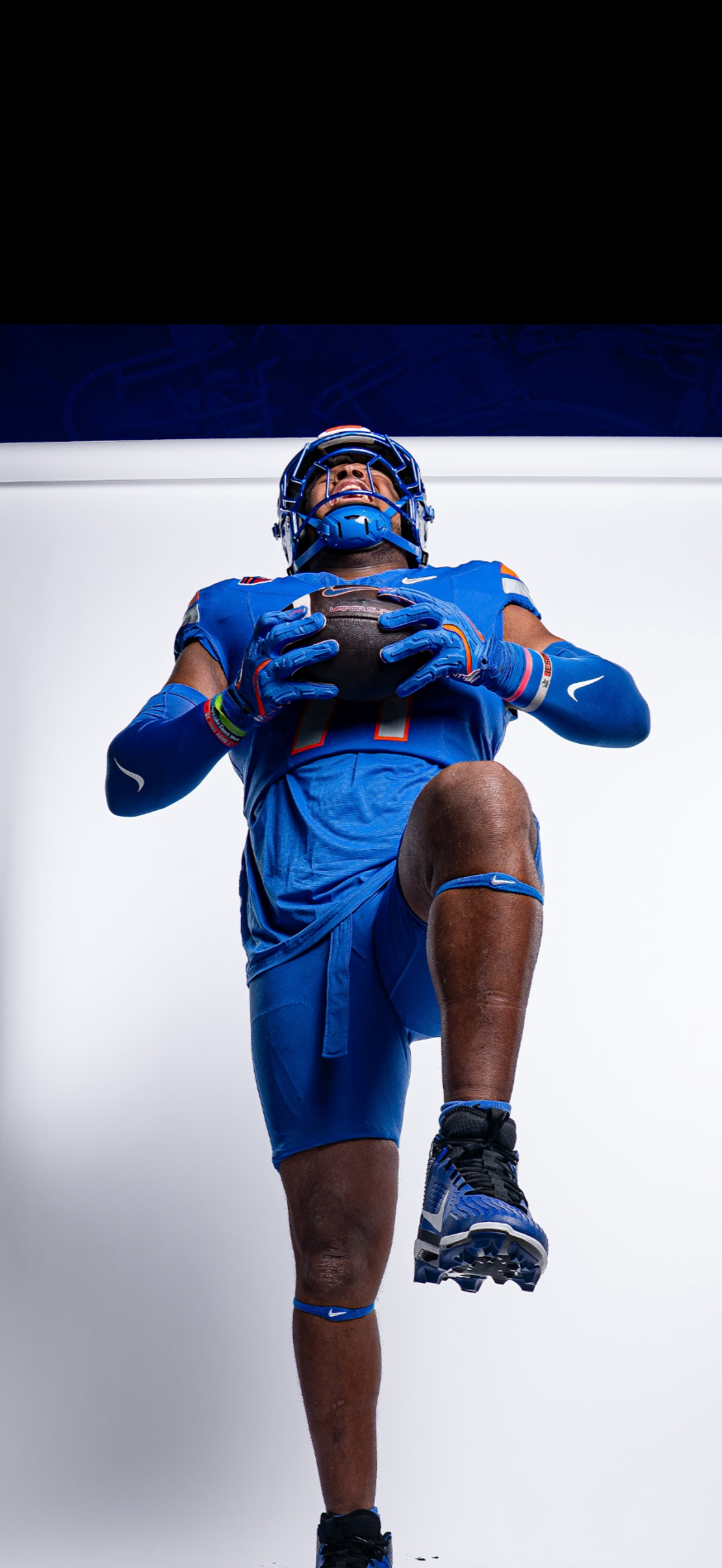 Tyler Ethridge, offensive tackle for Boise State football. Tyler is holding a ball with one knee up in a media photo.