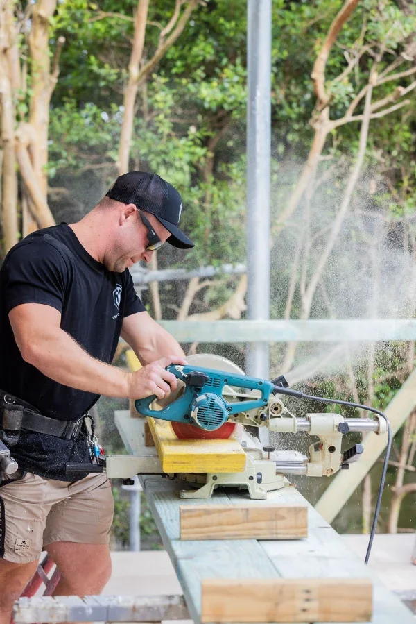 JTB builder cutting timber with a drop saw