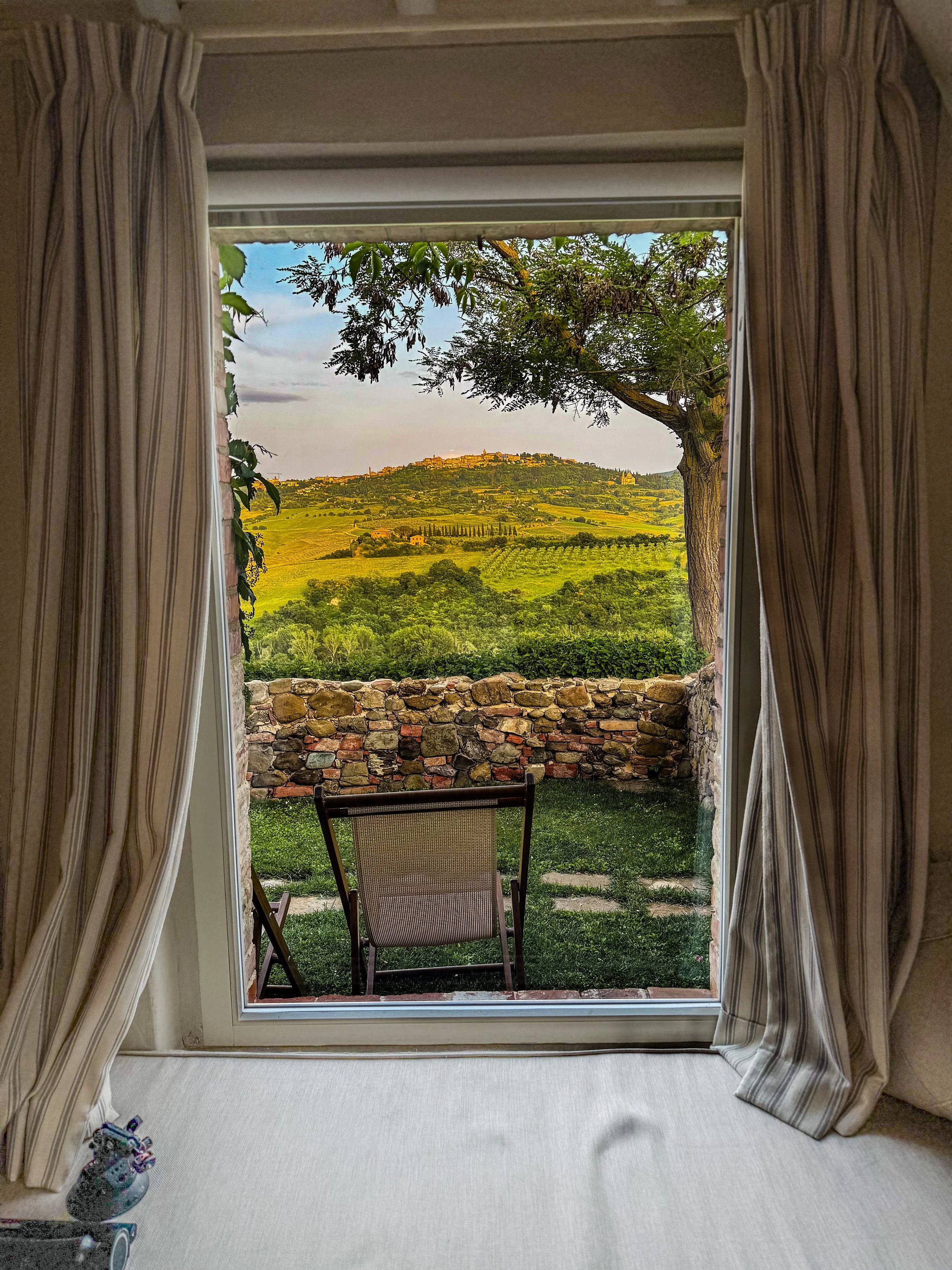 Rustic window framing golden vineyard landscape view from boutique hotel room with stone windowsill
