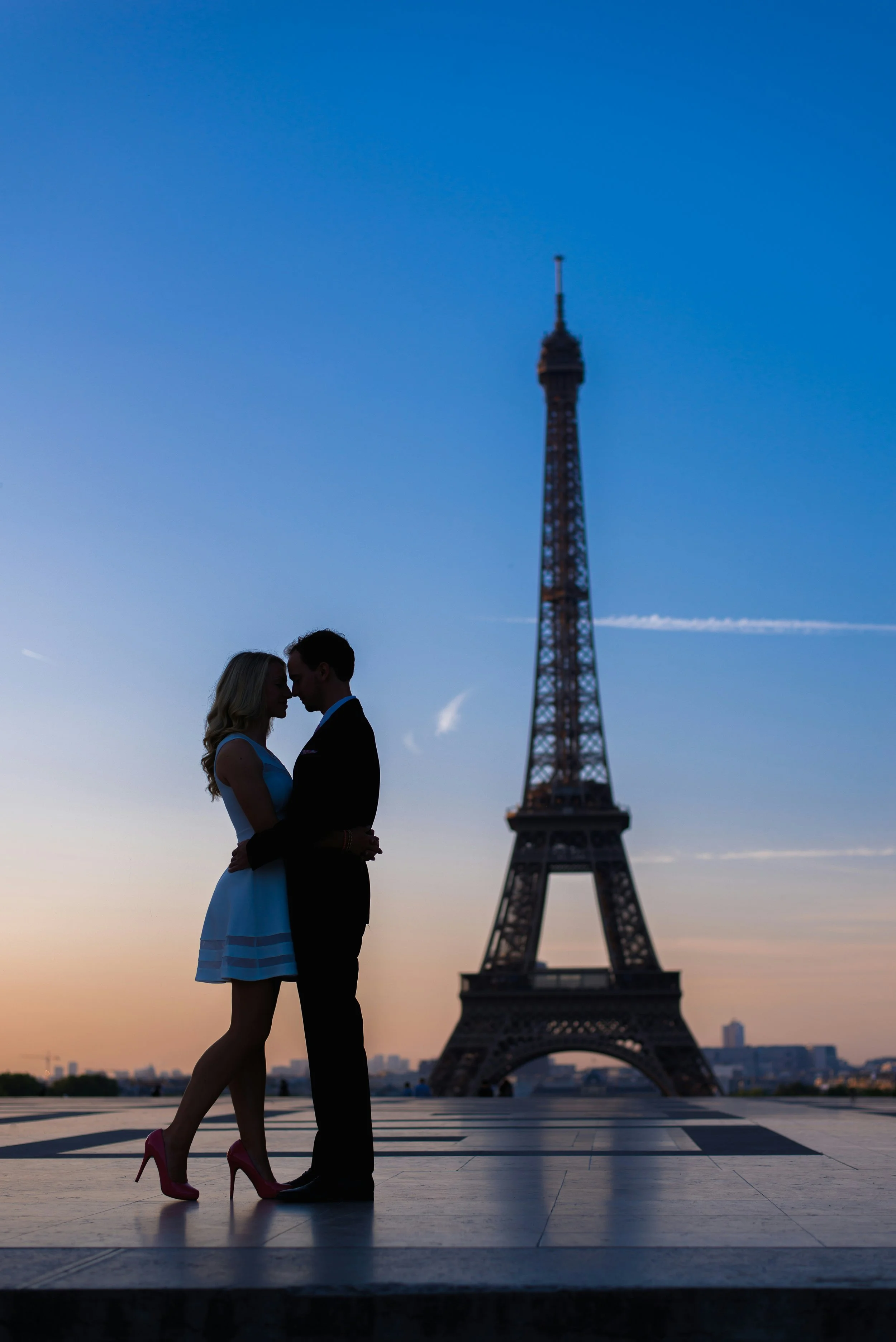 Couple silhouette embracing in front of illuminated Eiffel Tower at sunset in Paris