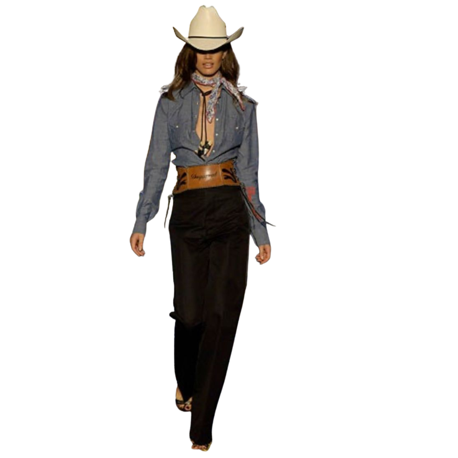 A woman wearing a cowboy hat, denim shirt, cowboy belt, scarf, and black pants.