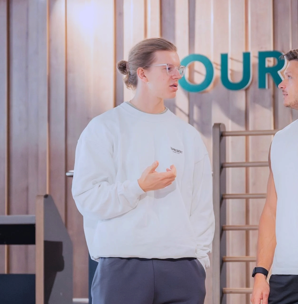 Bild von Moritz Grundmann von Vita Sports Club, er steht in einem Fitnessstudio und spricht dabei mit einer anderen Person