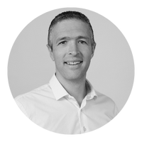 Black and white portrait of a smiling man in a white shirt, facing forward.