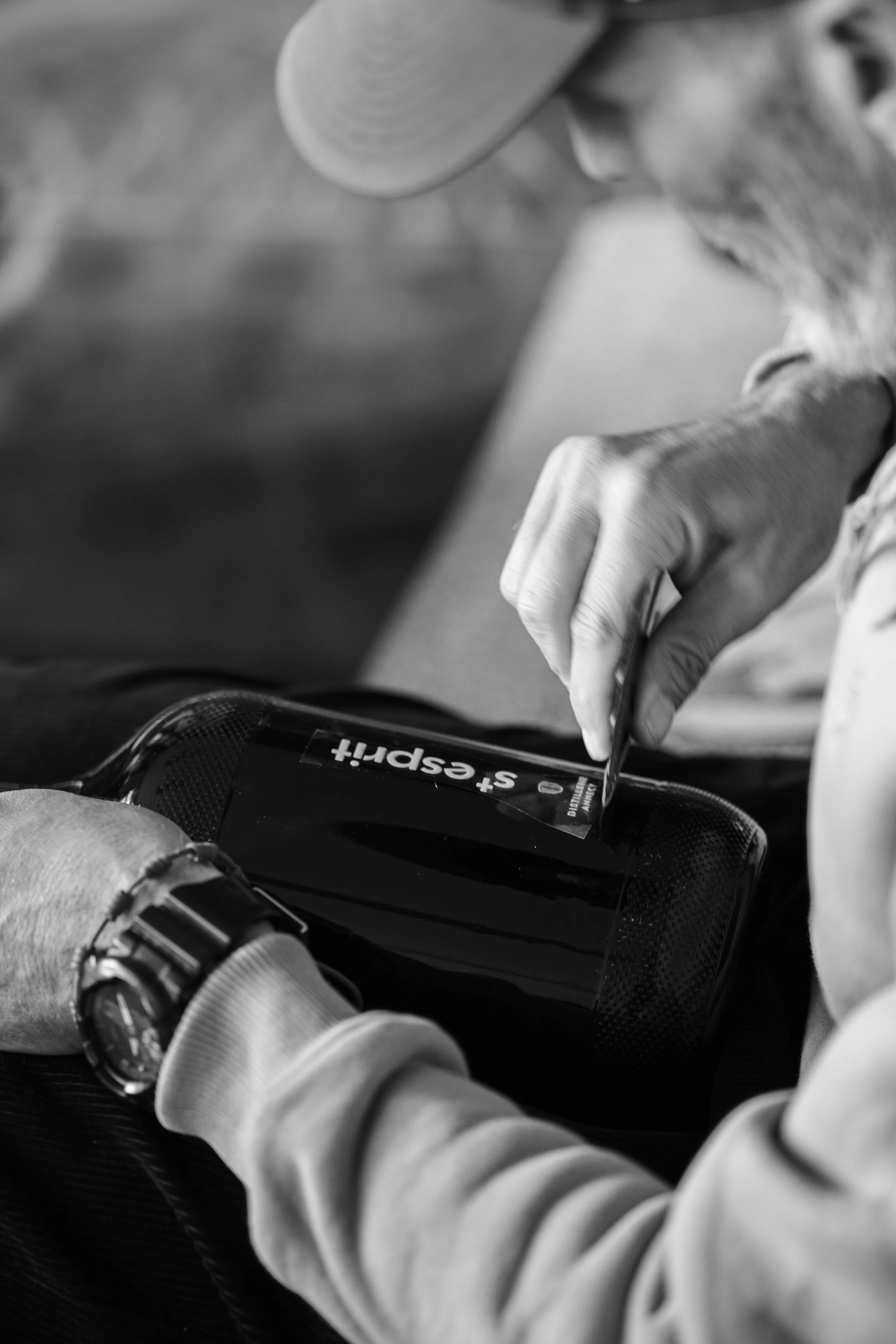 Une personne utilise une tablette ou un téléphone, avec l'inscription « +spread » visible sur l'écran, en noir et blanc.