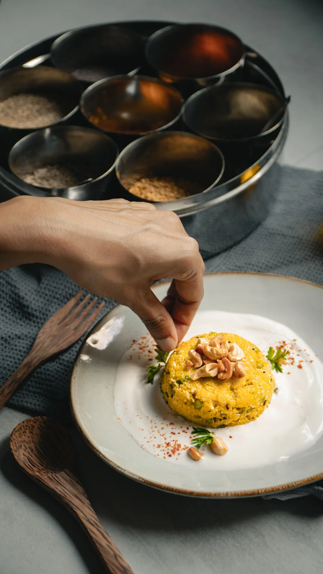 Person garnissant une assiette de couscous avec des noix et de la sauce