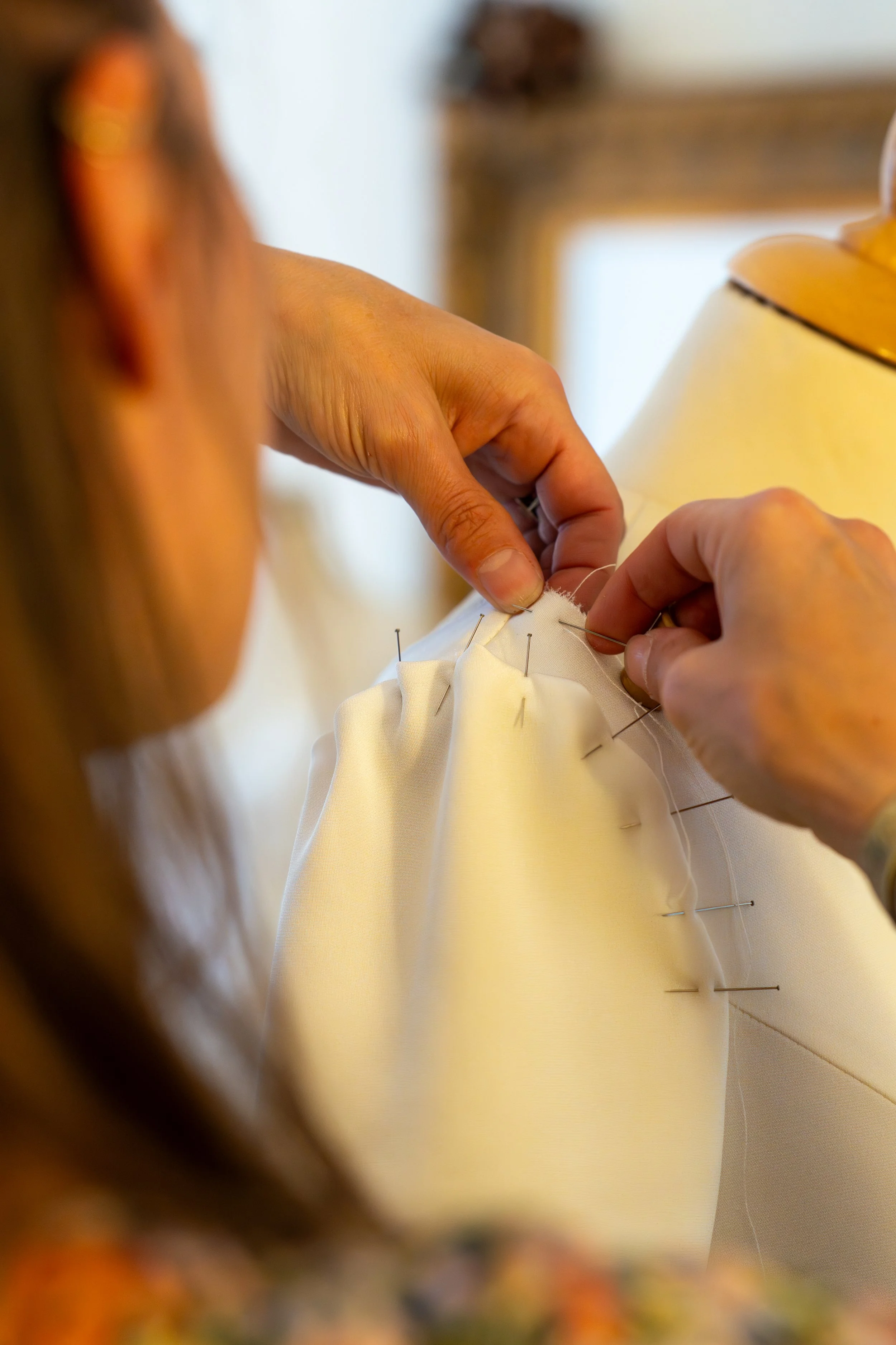 Une personne couse à la main une pièce de tissu blanc avec des épingles.