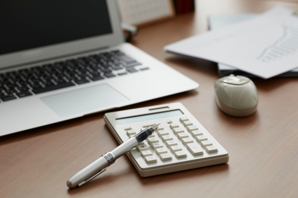 Calculator and pen on desk with laptop, professional business valuation and financial analysis