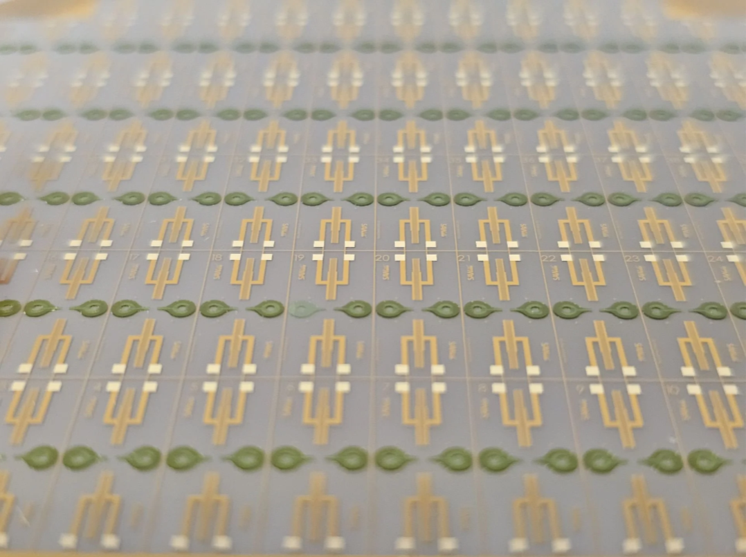 Sheet of electronic circuit prototypes with gold and green components.