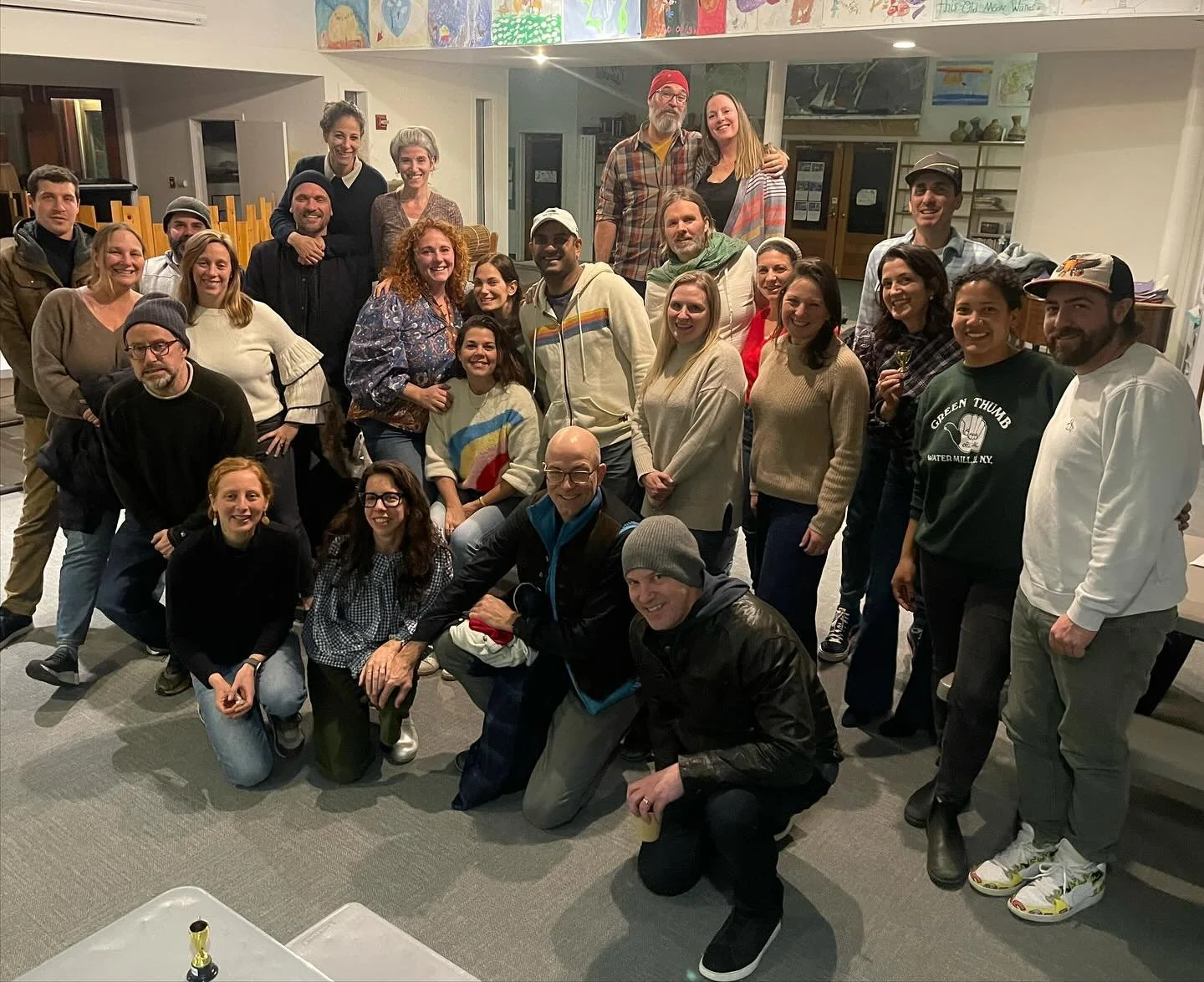 A large group of people gathered indoors, posing for a group photo, smiling and standing close together.