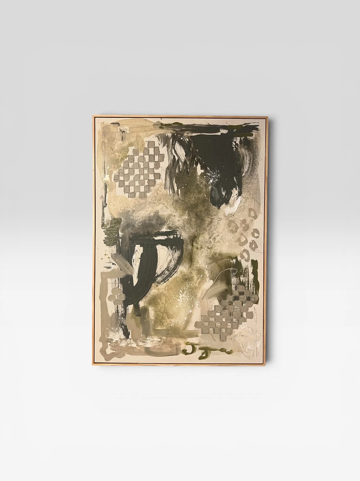 Abstract painting with black, beige, and green brushstrokes, geometric shapes, and textured patterns, framed and hanging on a plain wall.