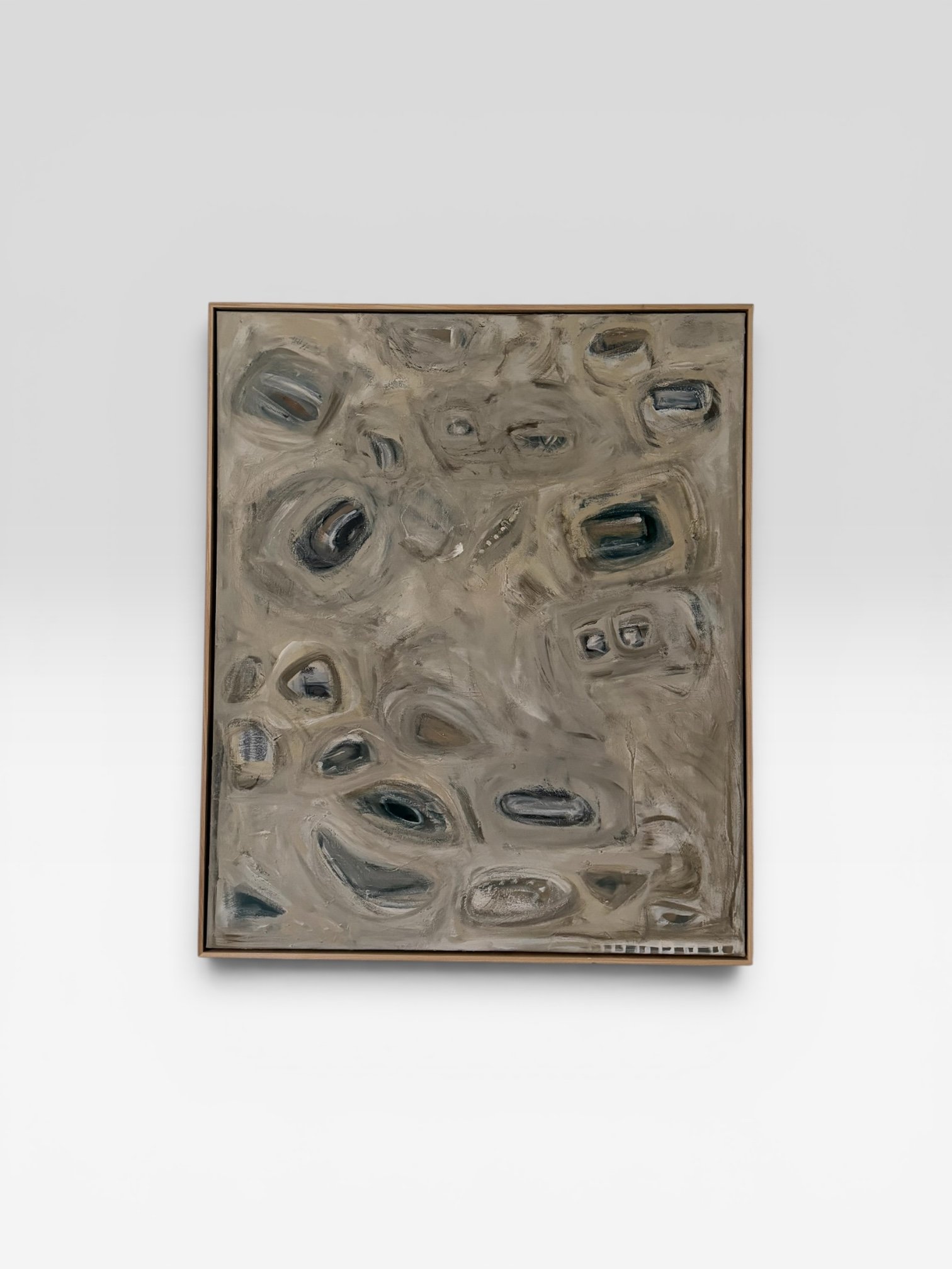 Abstract painting with oval and rectangular shapes in gray, black, and beige tones, framed and displayed on a white wall.
