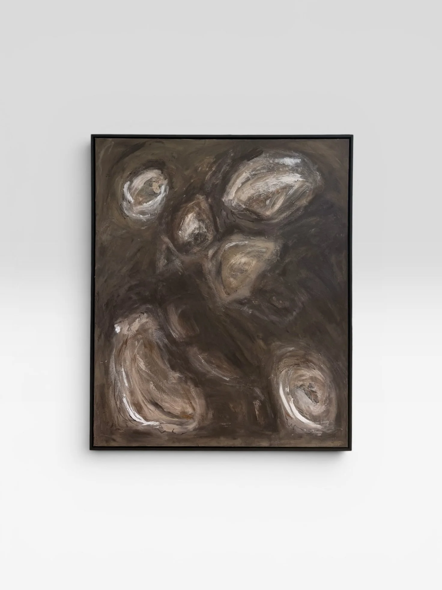 An abstract painting with swirling patterns in shades of brown, white, and beige, framed with a black border, hanging on a white wall.