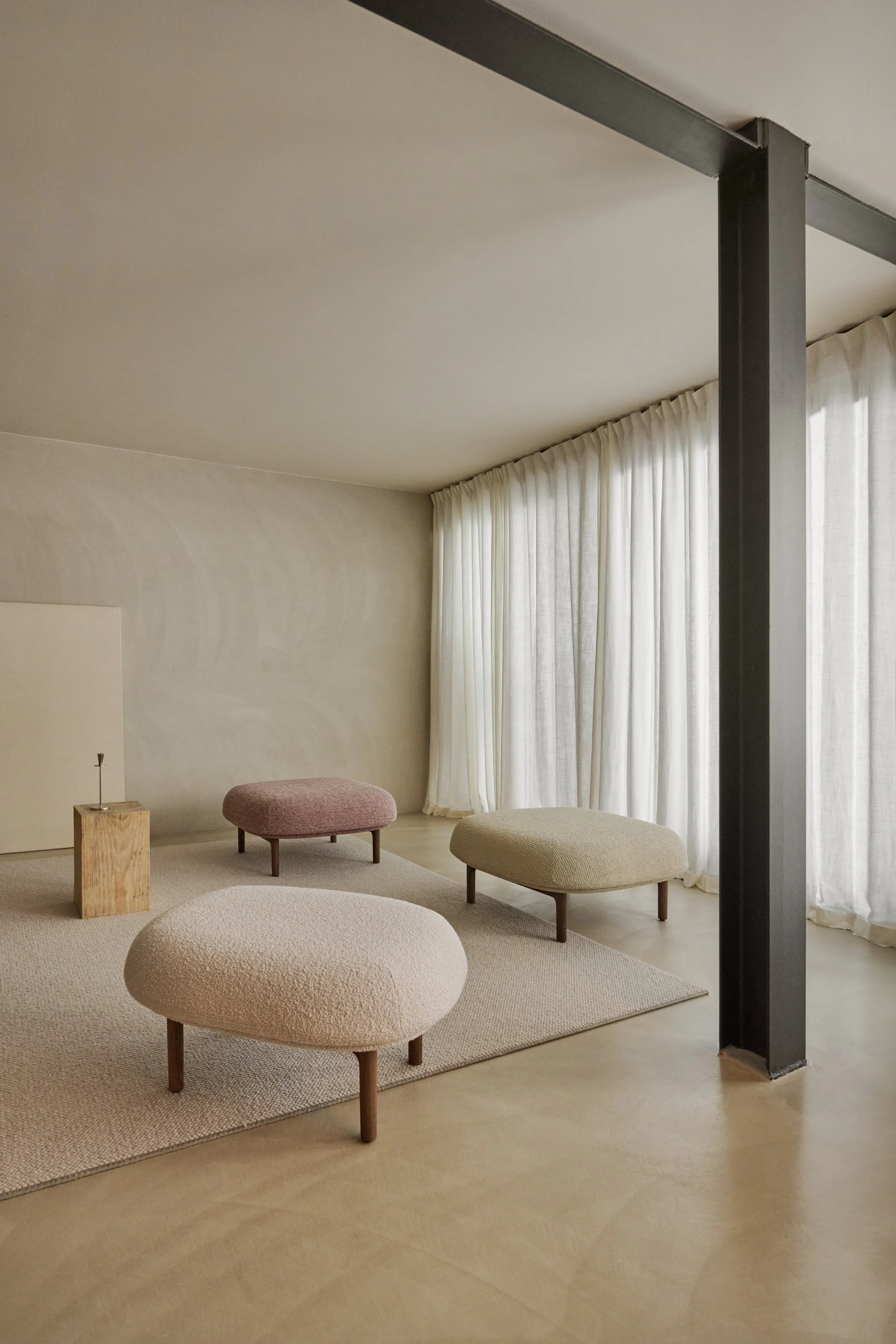 Mela Ottoman with a soft upholstered top resting on a solid wood frame, combining comfort and refined craftsmanship.