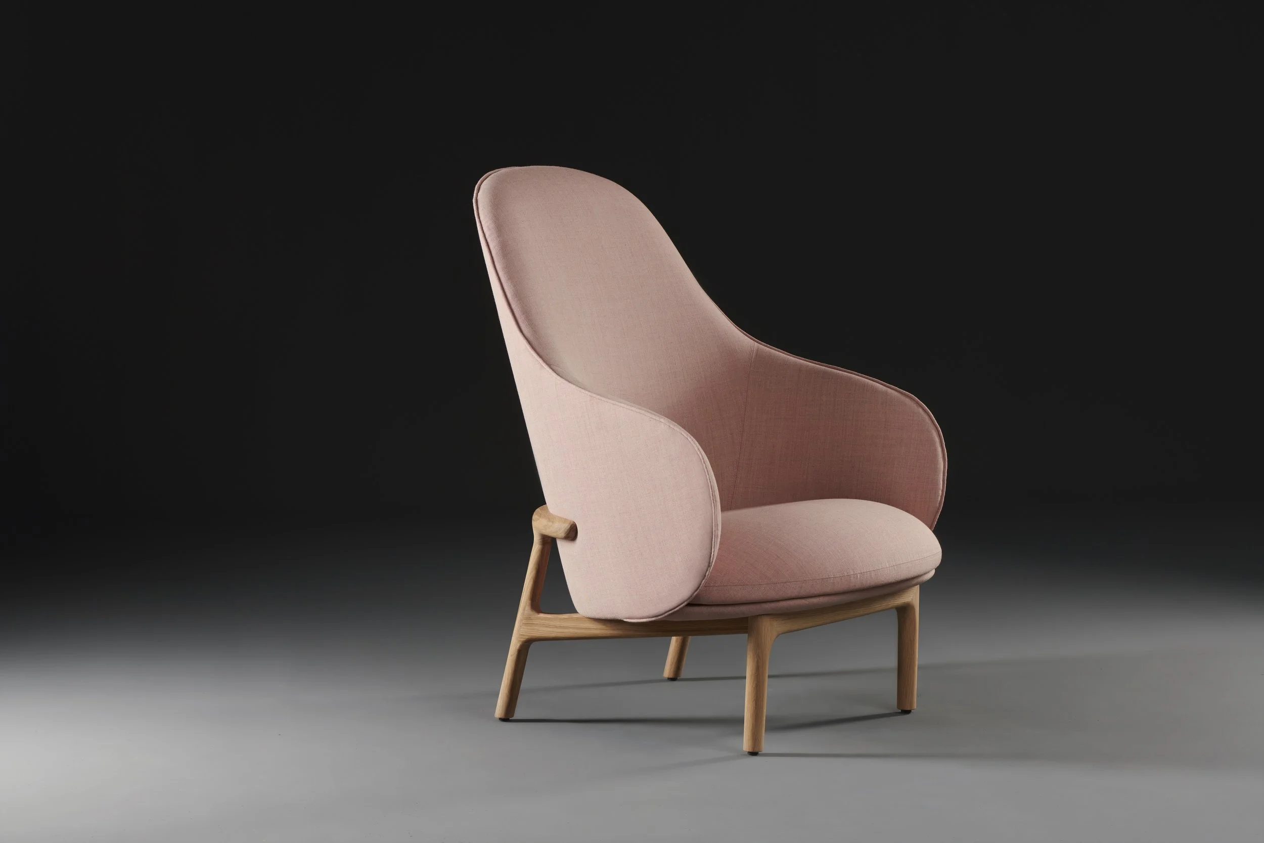 Mela armchair with soft upholstered seat and backrest supported by a solid wood frame.