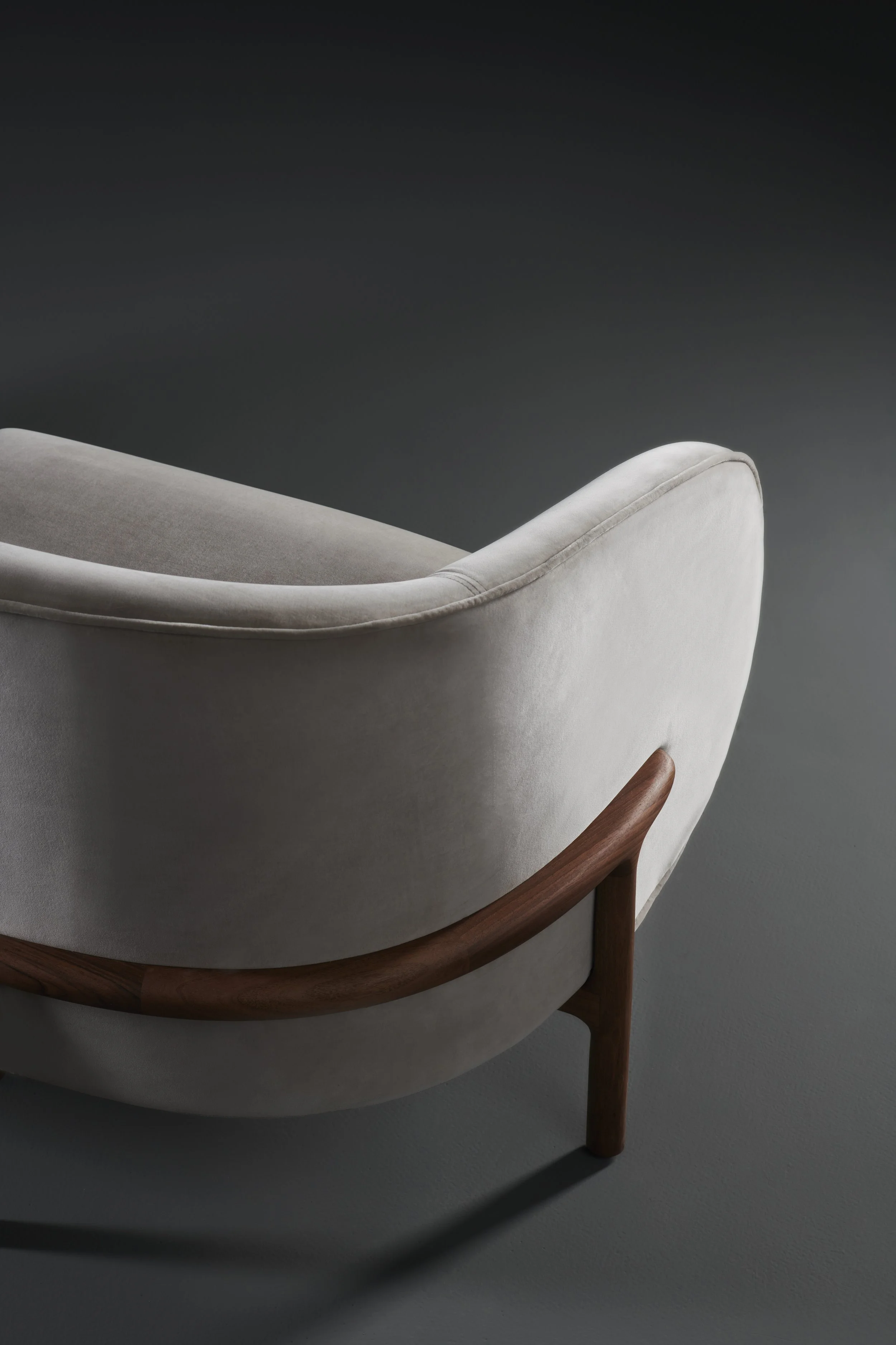 Side view of the Mela Lounge Two-Seater highlighting its gently curved seat, backrest, and solid wood frame.