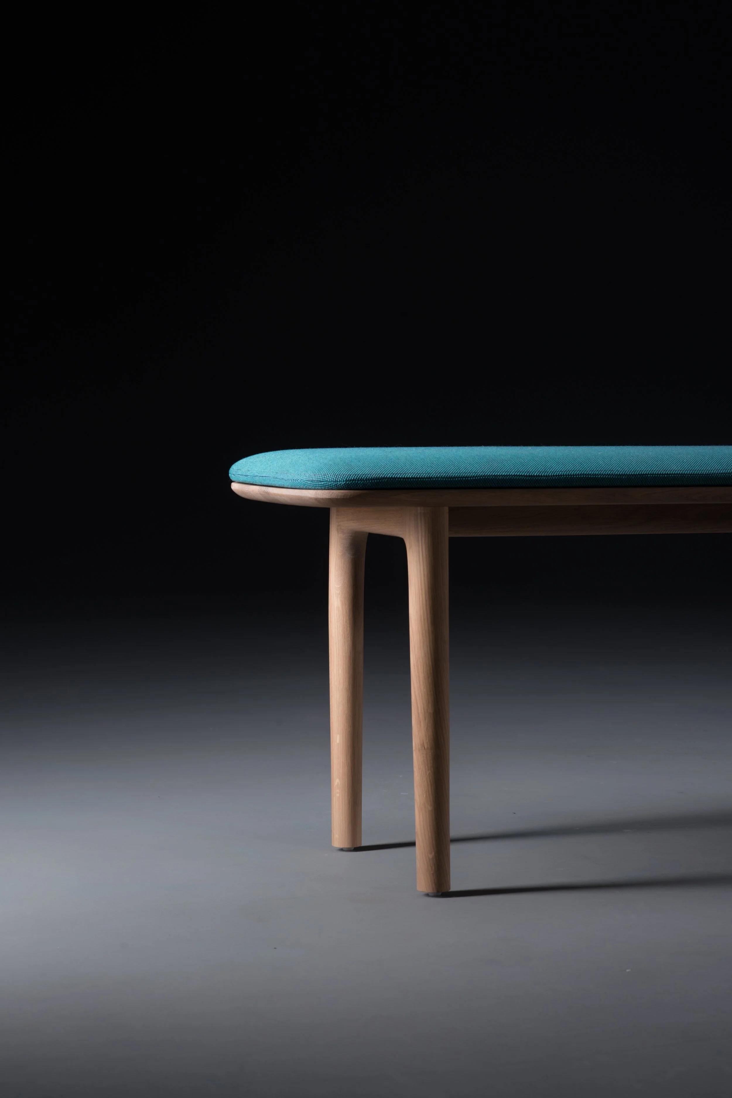 Neva bench featuring a solid wood frame and an upholstered seat in leather or fabric.