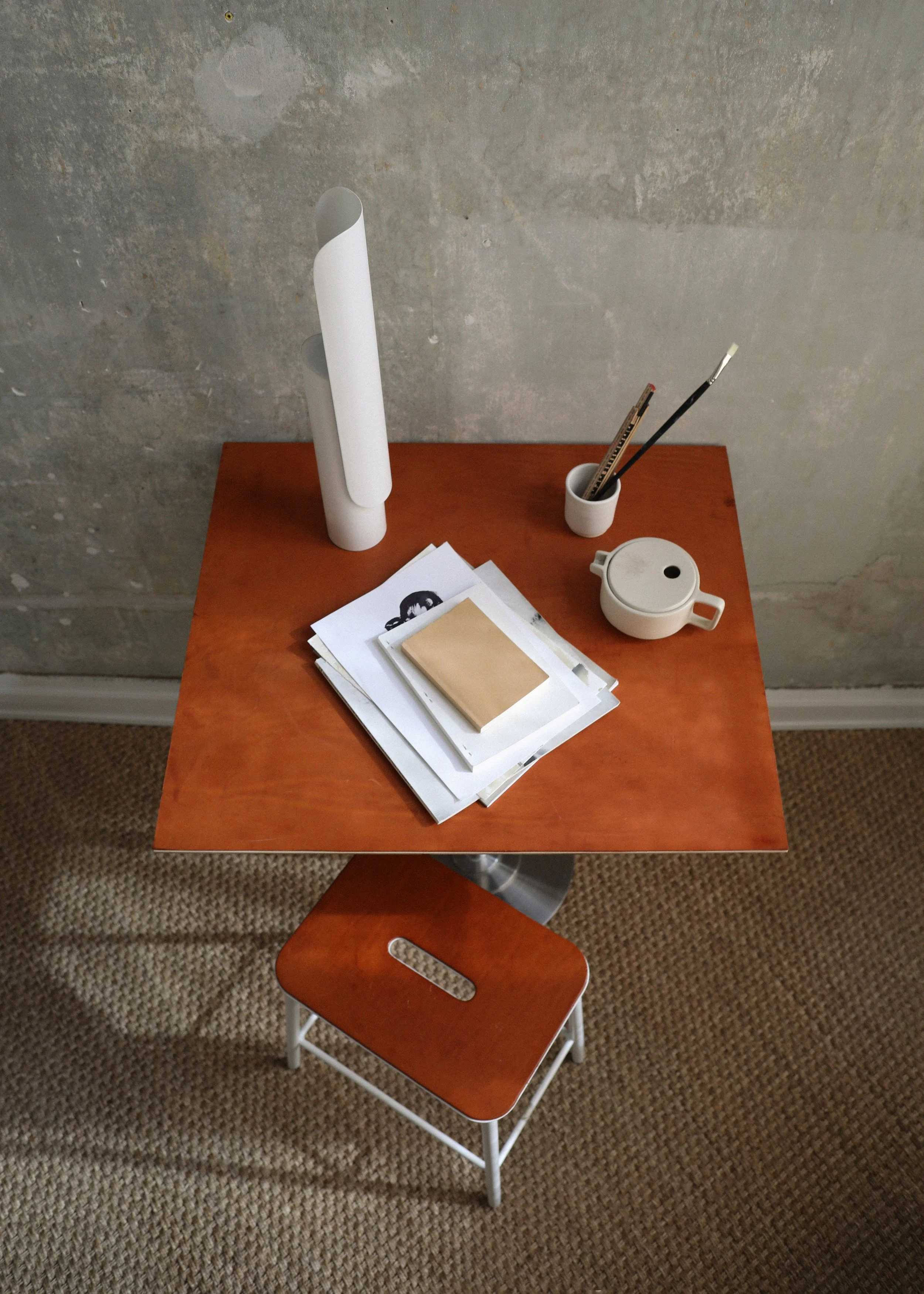 T Lamp illuminating a workspace, with a sculptural geometric form and tiltable head for versatile lighting angles.