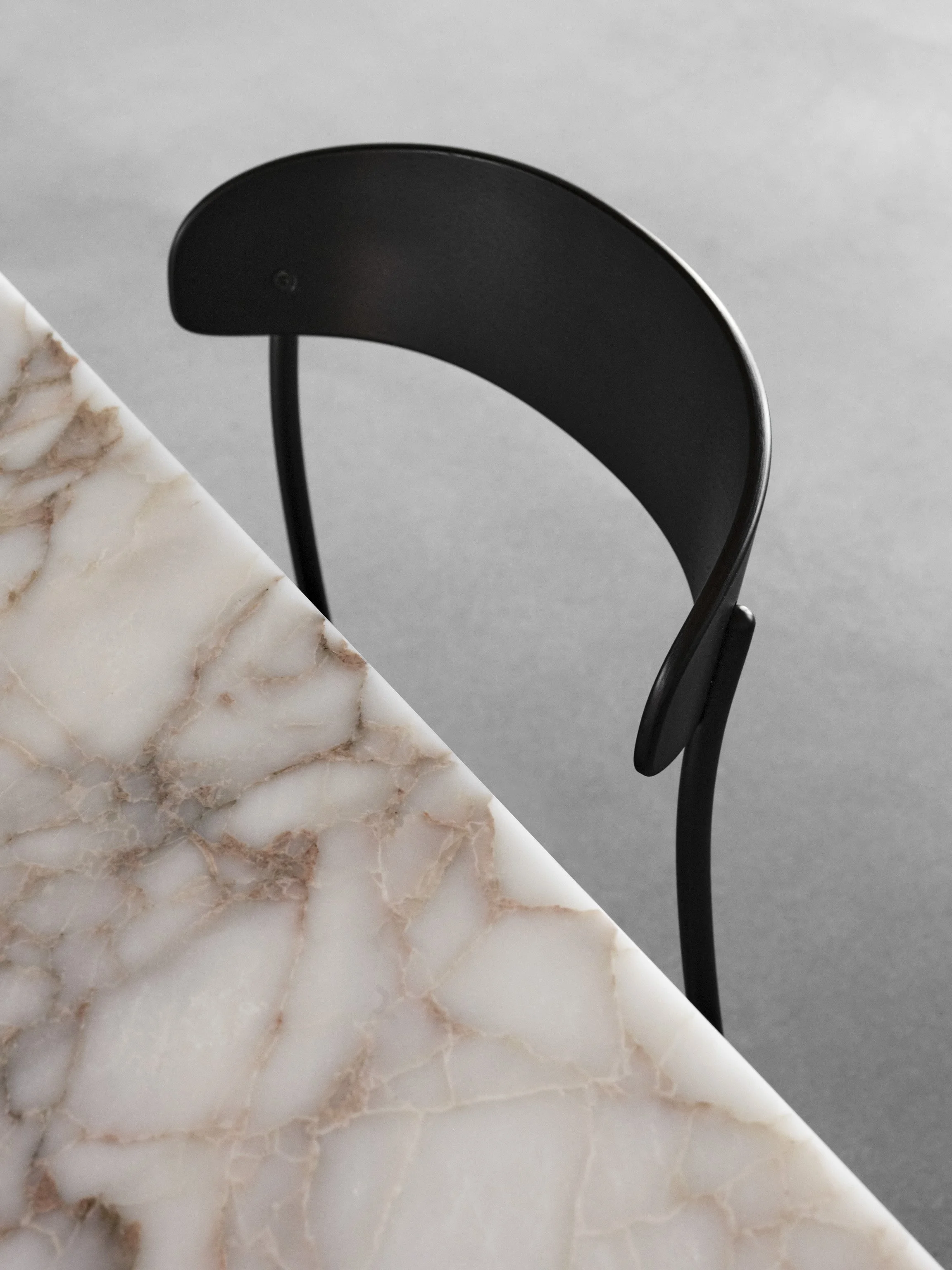 Detail of Missing Chair emphasizing the delicate curves of the seat and backrest framed by simple linear legs, creating a minimalist, sketch-like appearance