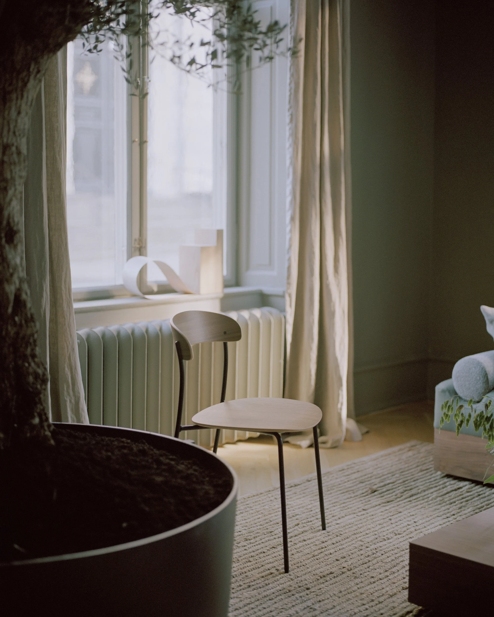 Detail of Missing Chair emphasizing the delicate curves of the seat and backrest framed by simple linear legs, creating a minimalist, sketch-like appearance.