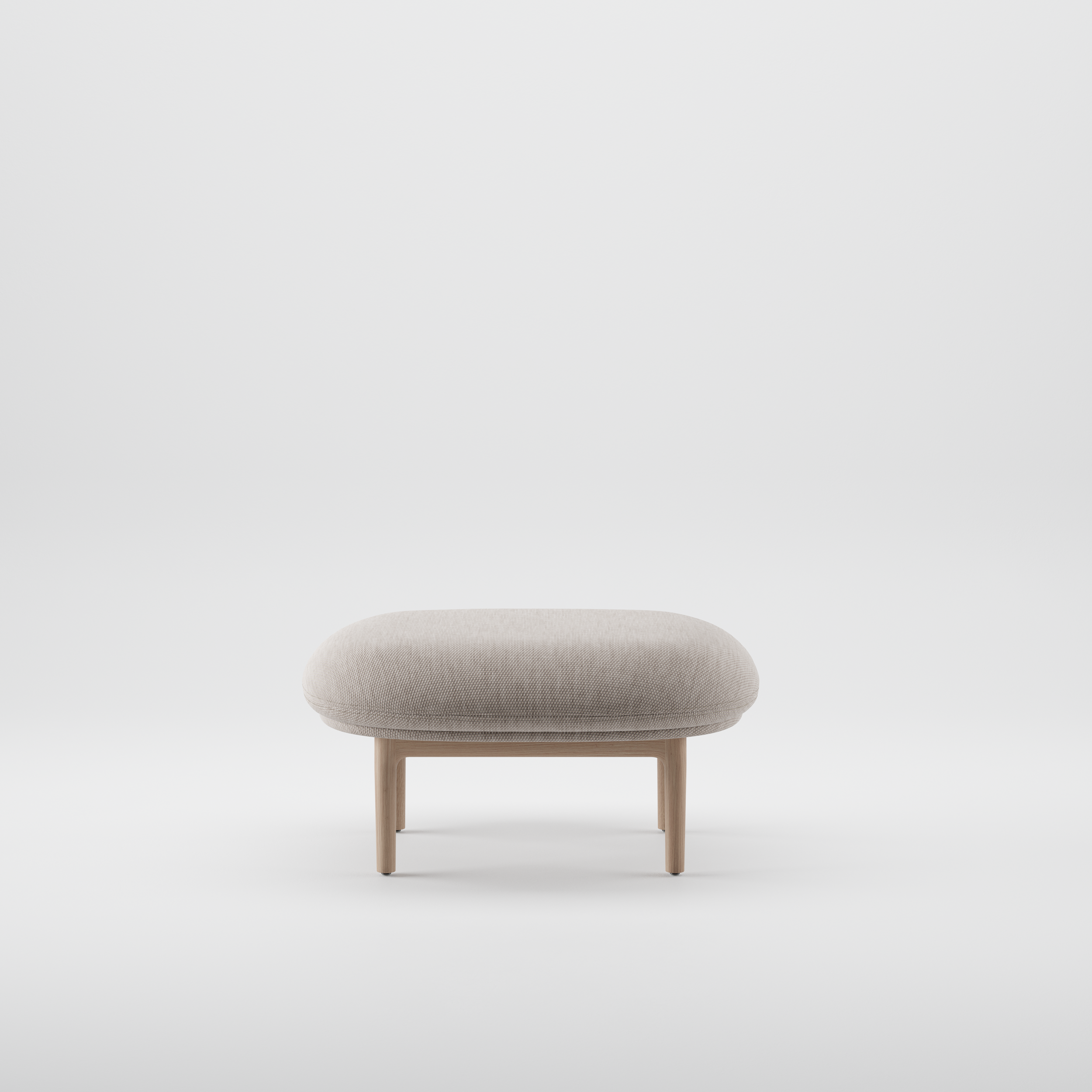 Mela Ottoman with a soft upholstered top resting on a solid wood frame, combining comfort and refined craftsmanship.