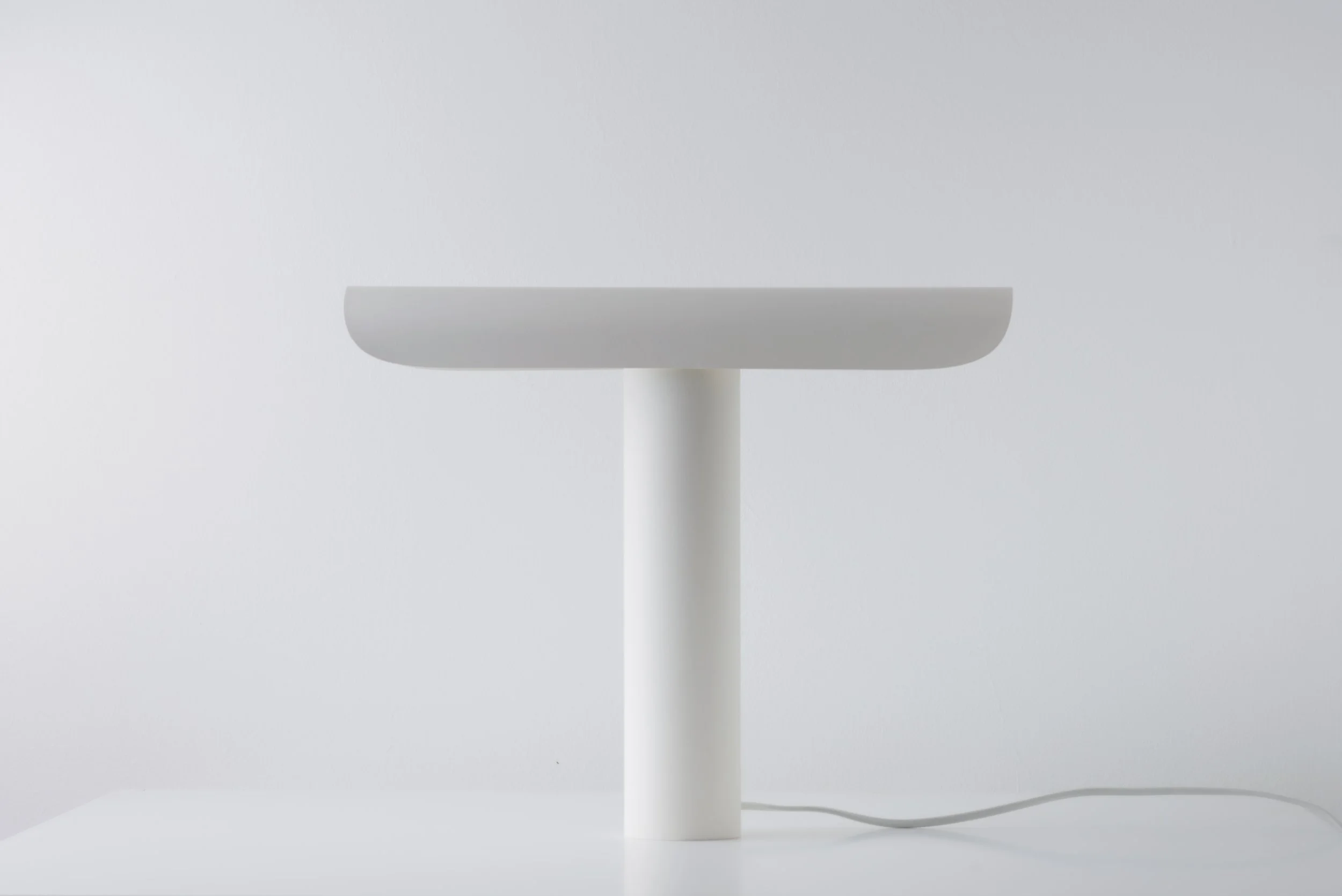 T Lamp showcasing clean lines and geometric design, with a simple mechanism allowing the lamp to tilt and cast light dynamically.