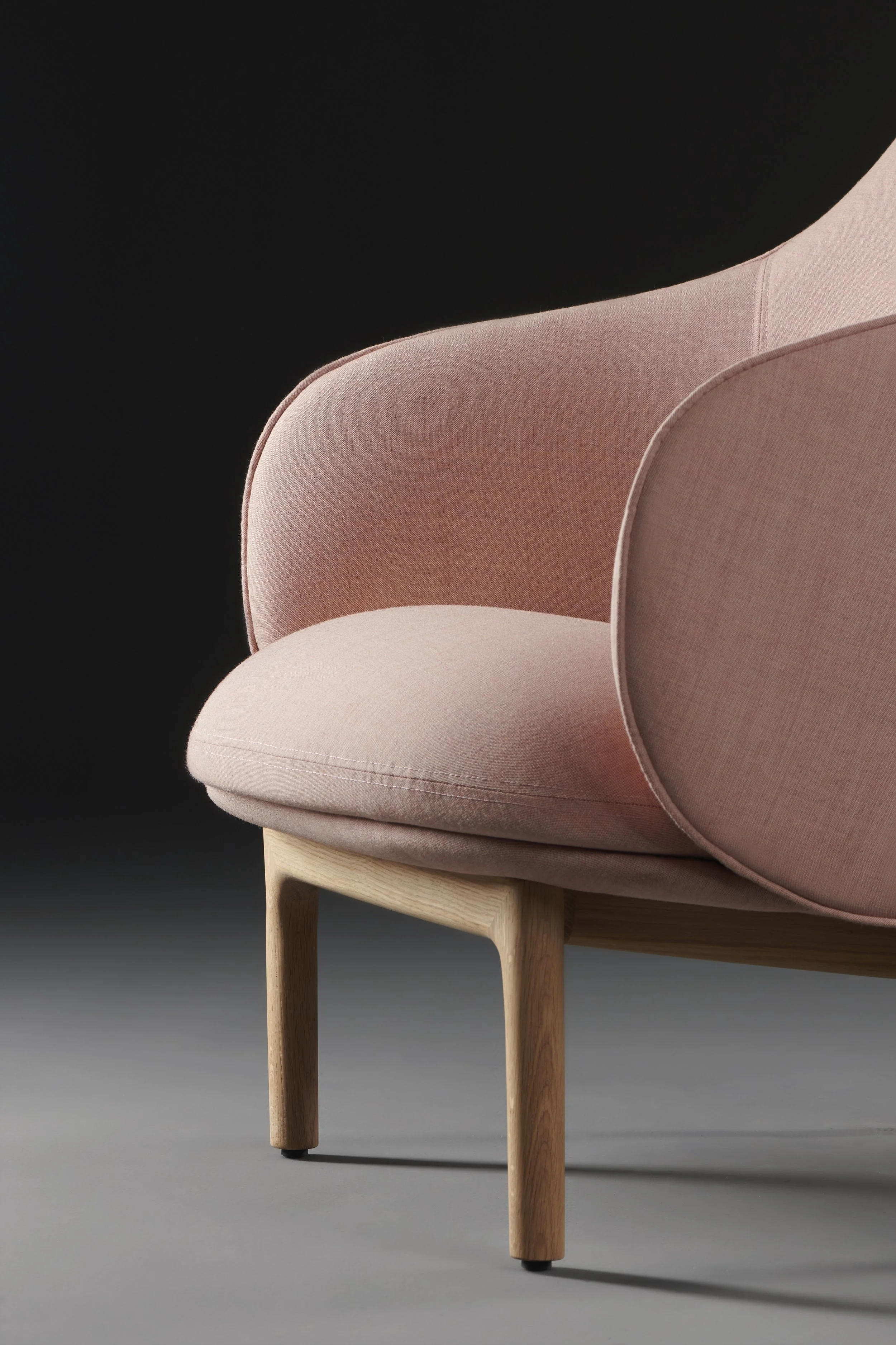 Mela armchair with soft upholstered seat and backrest supported by a solid wood frame.