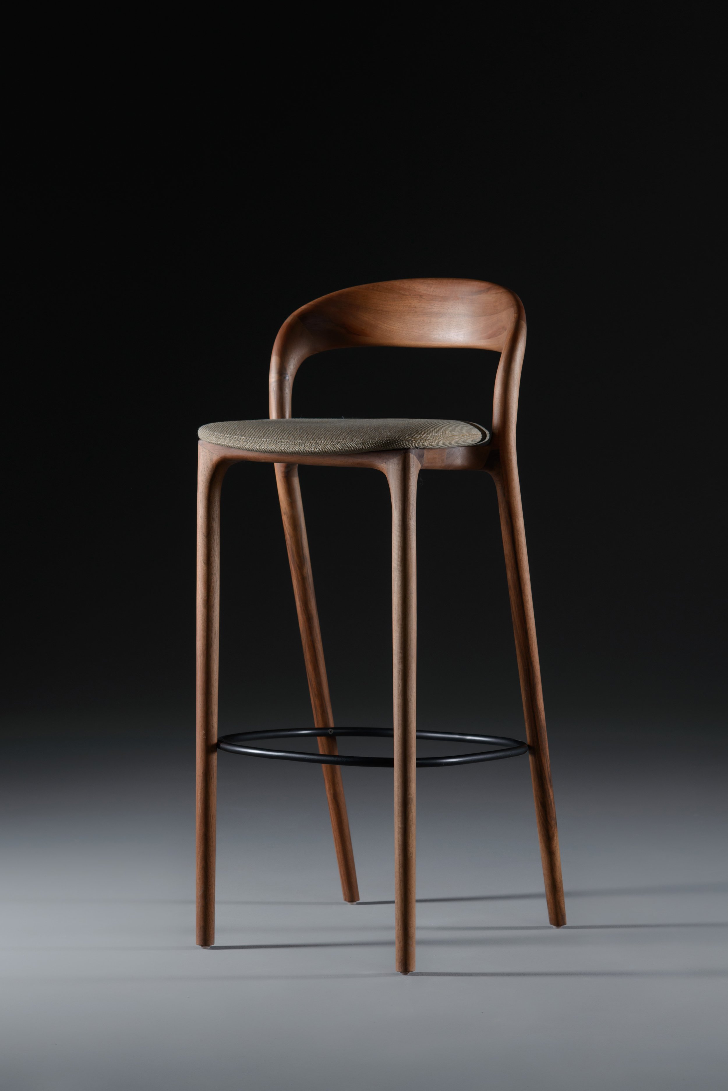 Neva Light bar chair featuring a sculpted wooden frame and upholstered seat, shown from a three-quarter angle.