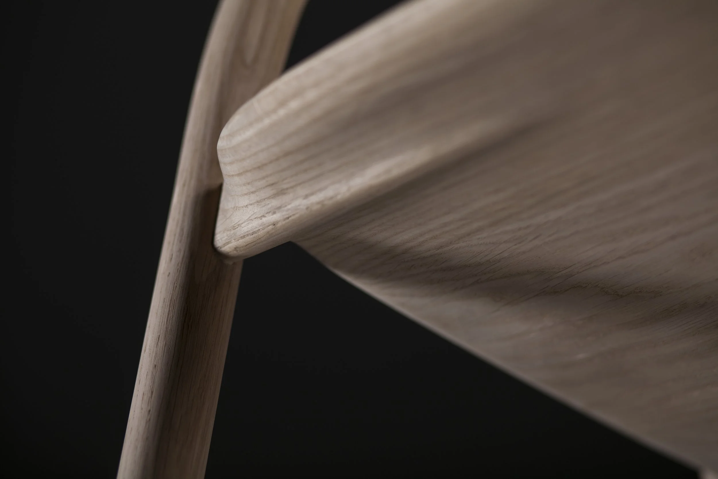 Close-up of Neva Chair backrest and armrest showing seamless wood craftsmanship