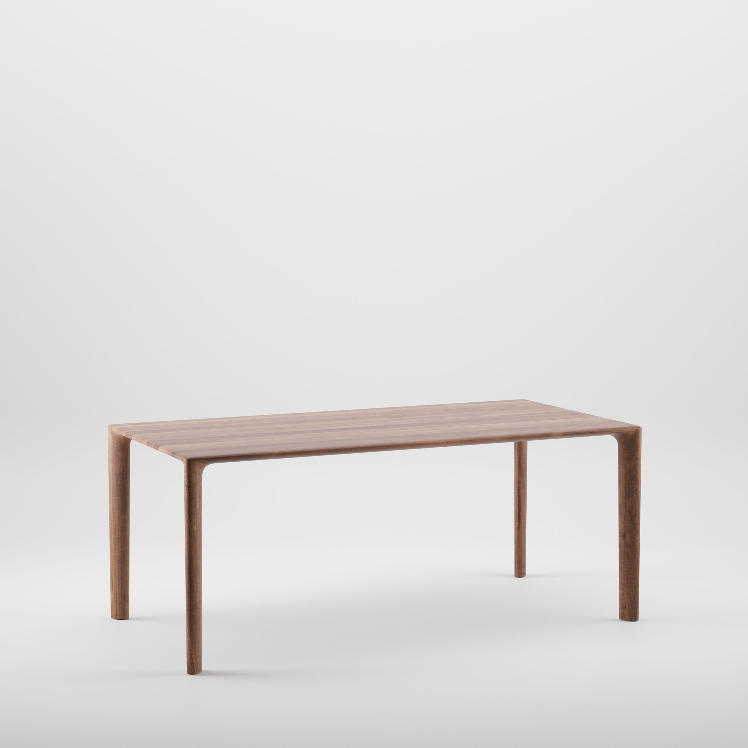 Three-quarter view of the Mela Table showing its smooth, sculpted wooden top and rounded corners.