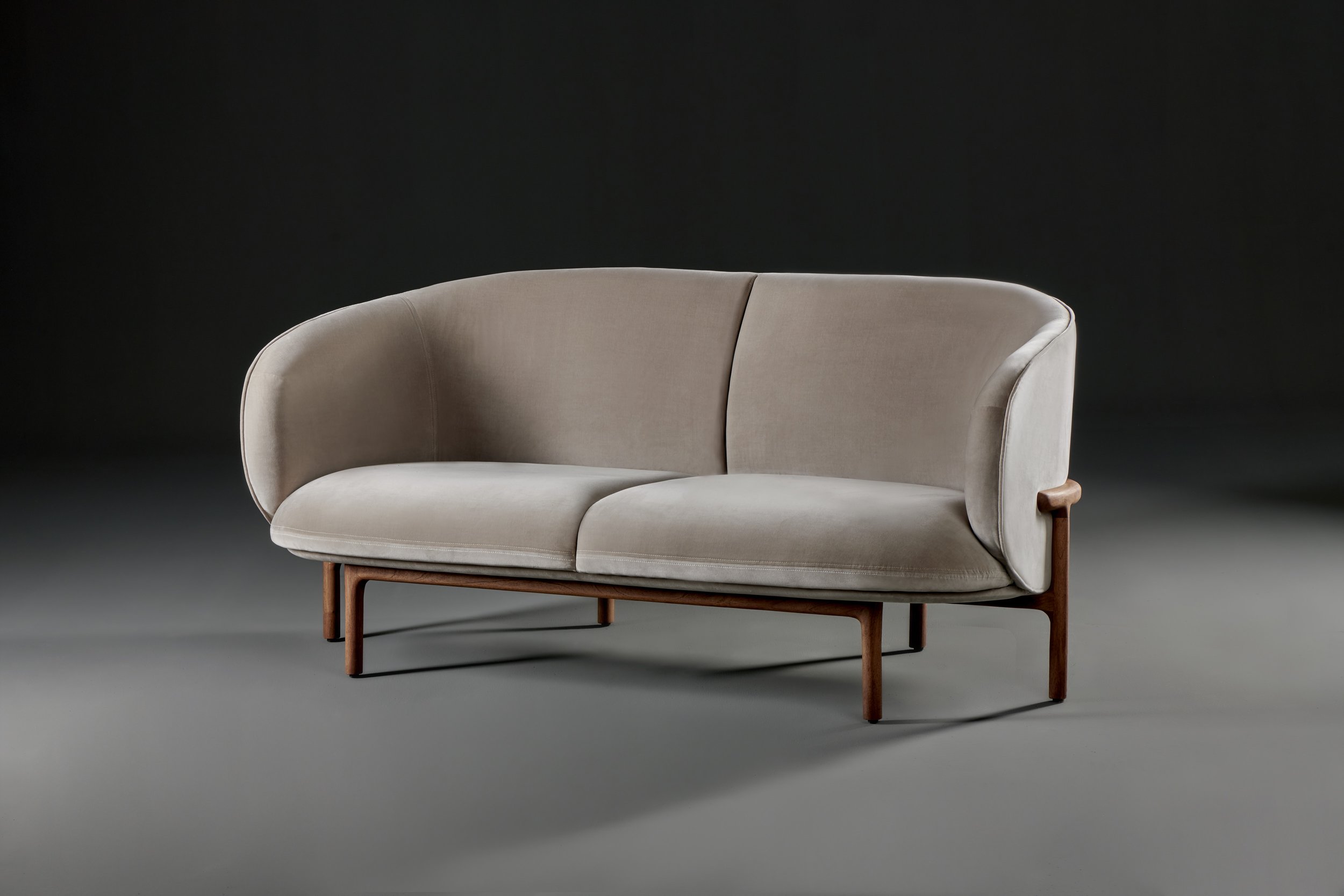 Mela Lounge Two-Seater with softly contoured upholstered seat and backrest, supported by a solid wood frame.