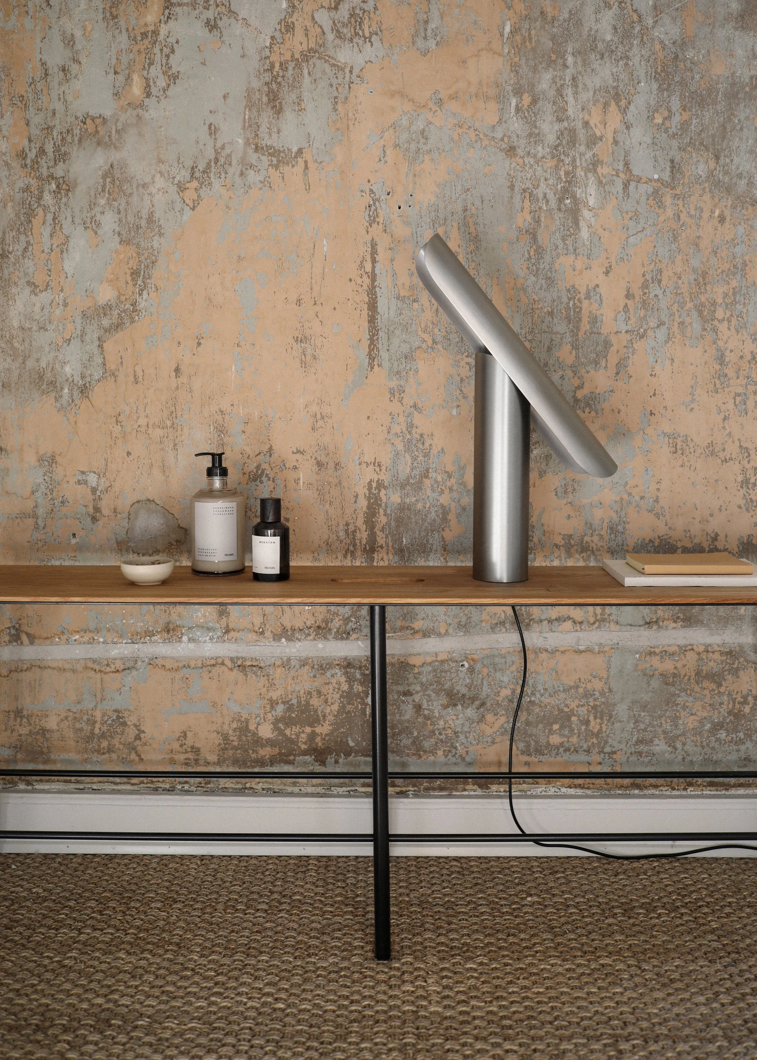 T Lamp illuminating a workspace, with a sculptural geometric form and tiltable head for versatile lighting angles.