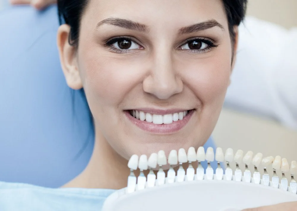Close-up of a woman smiling at a dental color palette in a dental office.