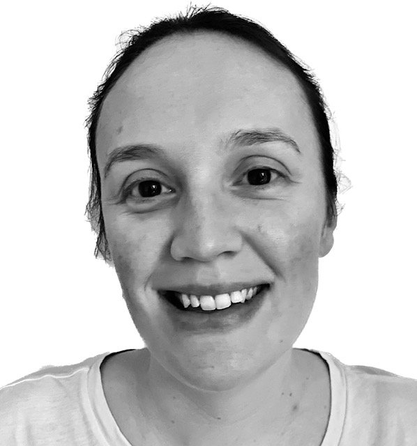 Black and white photo of a smiling woman with dark hair pulled back, wearing a light-colored shirt.